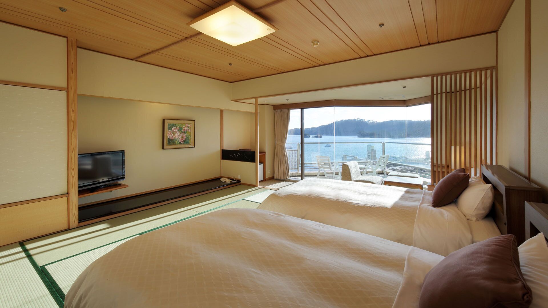 A hotel room with a large bed, a TV, a painting, and a view of the water.