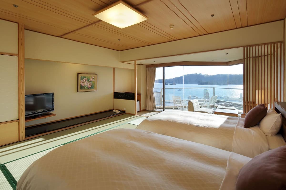 Habitación de hotel con una cama grande, televisión, un cuadro y vista al agua.