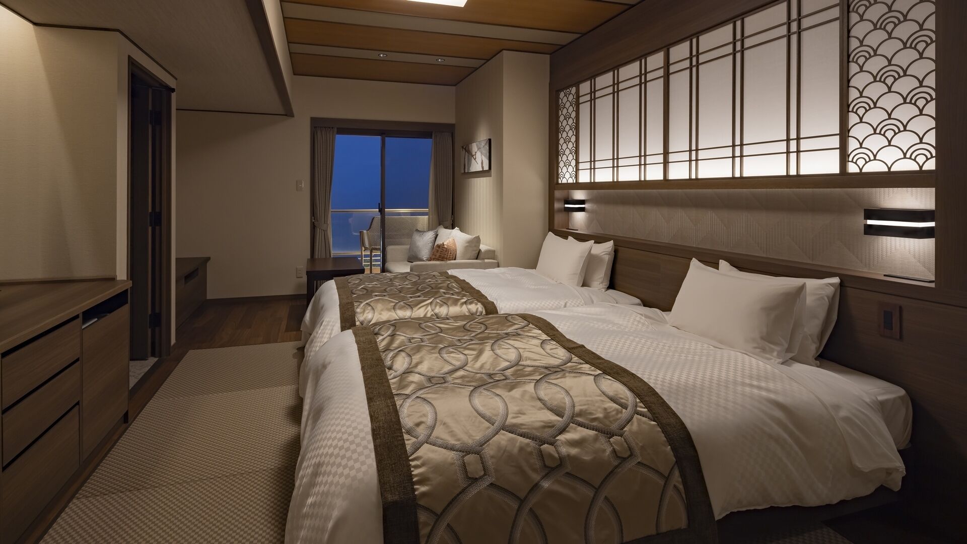 A hotel room with a large bed, a desk, a chair, and a view of the outside.