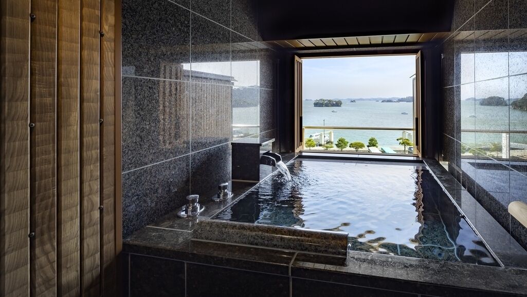 A spa area with a view of the sea, a hot tub, and a wooden panel wall.