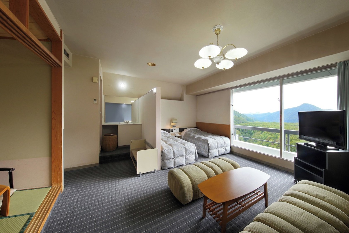 A hotel room with a bed, a TV, a dining table, and a sofa.