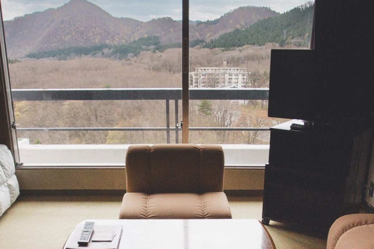 A room with a sofa, a table, and a TV.