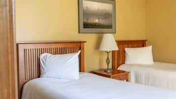Een hotelkamer met twee bedden, een nachtkastje met een lamp en een lijst aan de muur.
