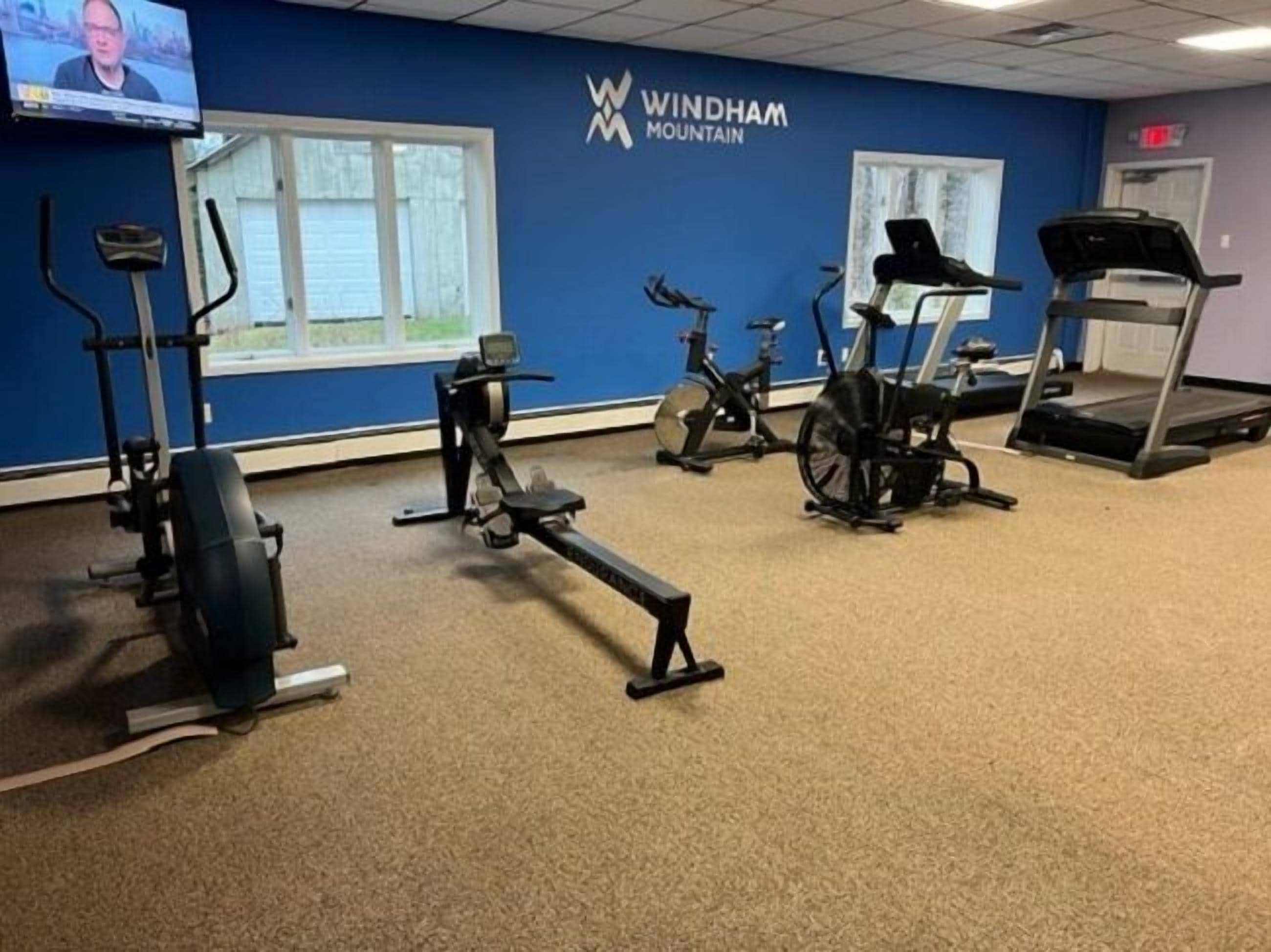 A gym with various exercise equipment including a treadmill, stationary bikes, and a rowing machine.