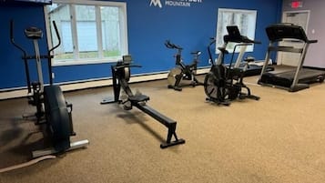 A gym with various exercise equipment including a treadmill, stationary bikes, and a rowing machine.