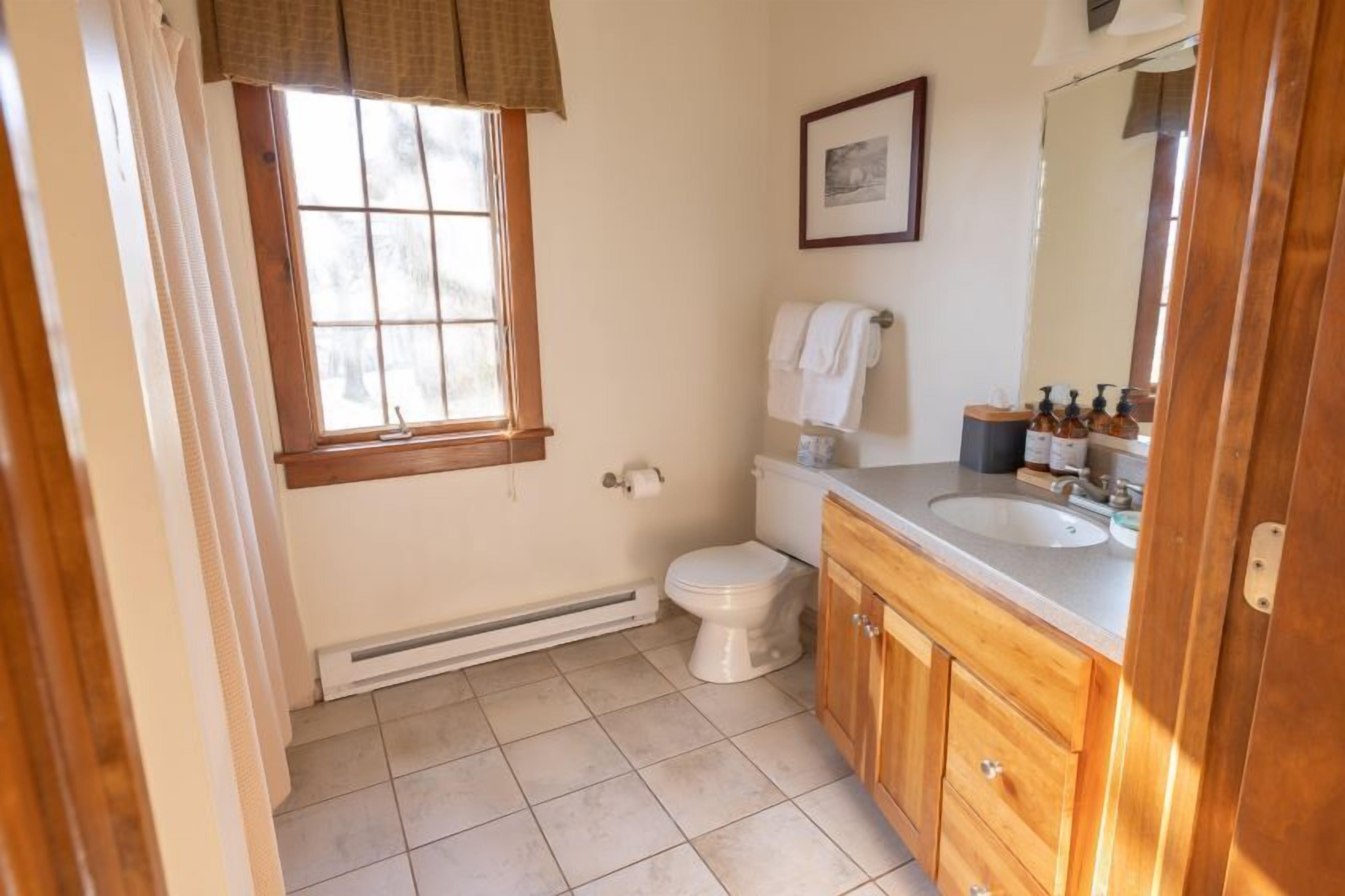 Un baño con inodoro, lavamanos y ventana.
