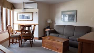 A living room with a grey sofa, wooden coffee table, and a dining table with chairs.