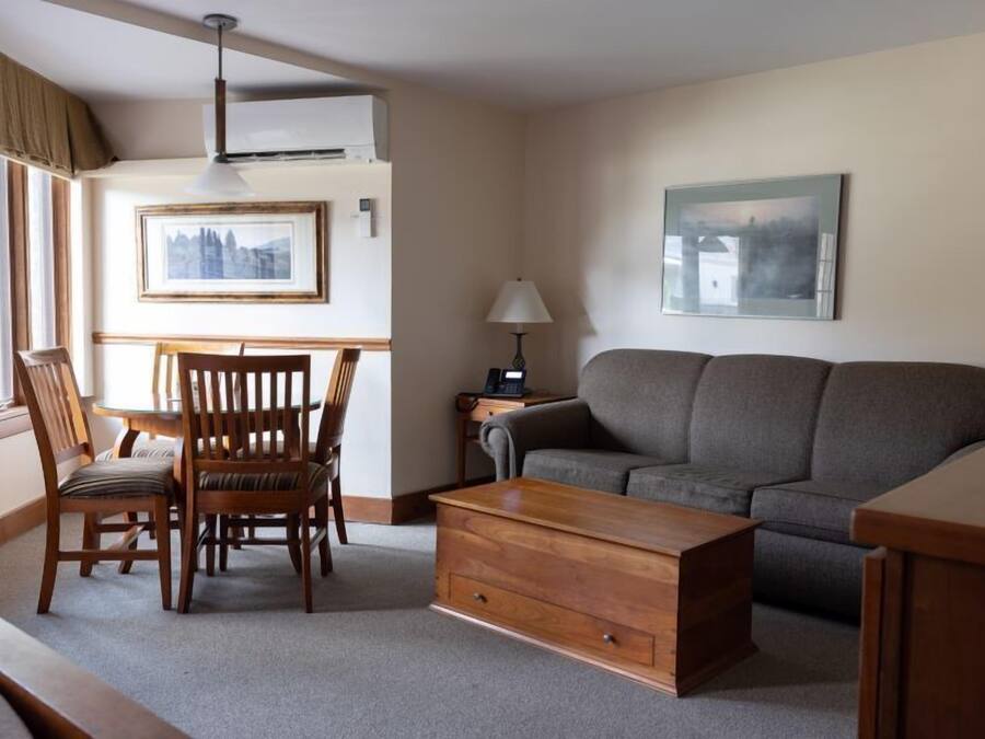 A living room with a grey sofa, wooden coffee table, and a dining table with chairs.