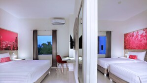 Habitación de hotel con dos camas, un escritorio, una silla y un ventanal grande.
