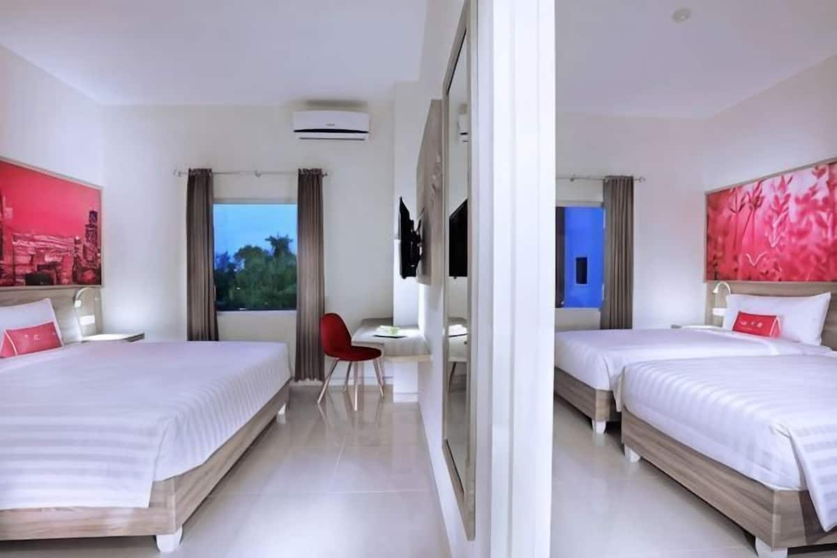 A hotel room with two beds, a desk, a chair, and a large window.