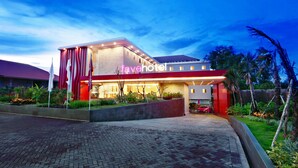 Un hotel moderno con una entrada destacada, fachada bien iluminada y un área de jardín ajardinada.