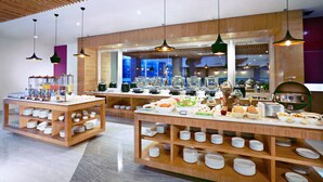 Una mesa de buffet con diferentes opciones de comida y utensilios, muebles de madera y lámparas colgantes.