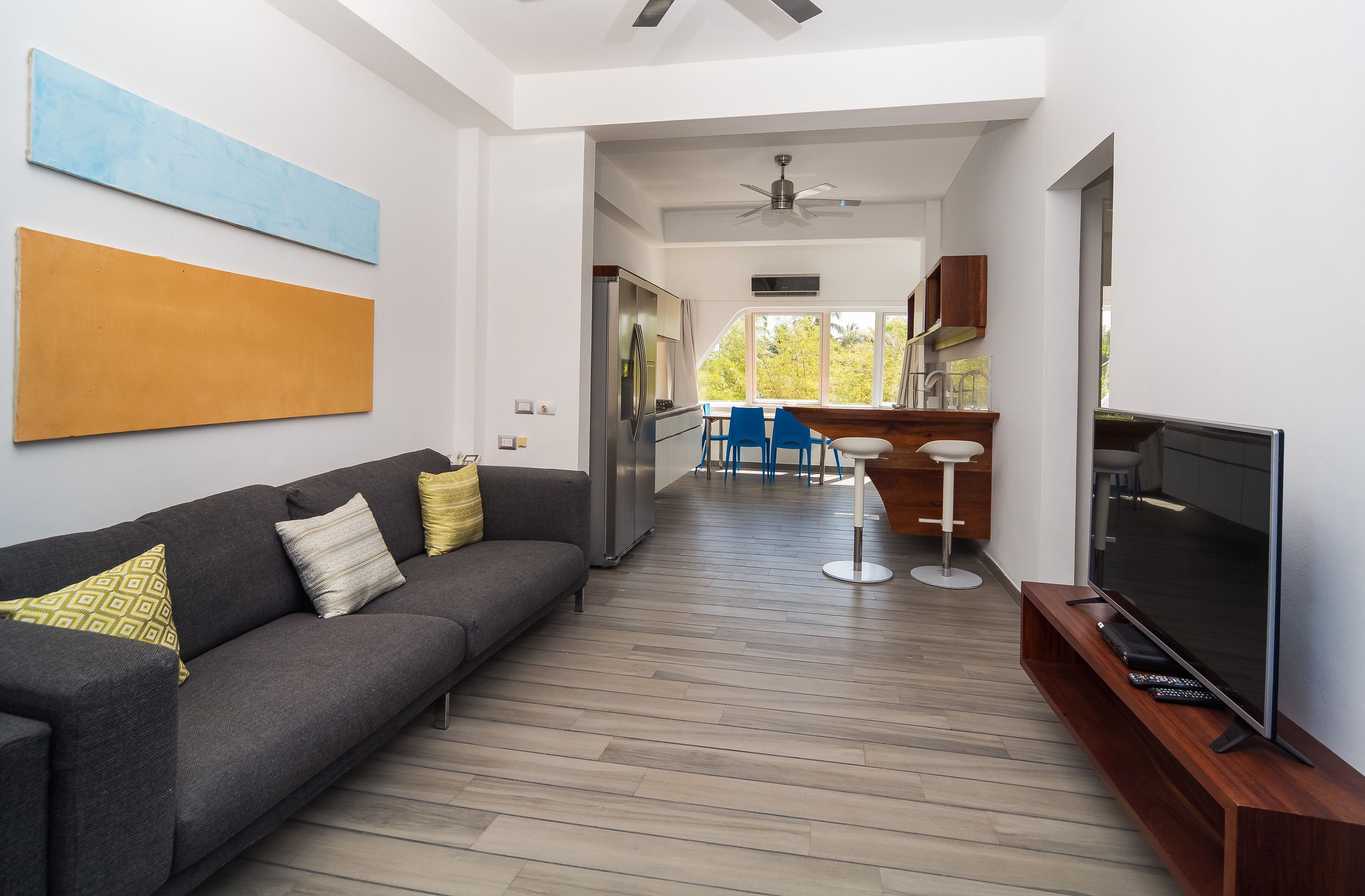 Una sala de estar moderna con un sofá, televisión y un comedor con sillas y una mesa.