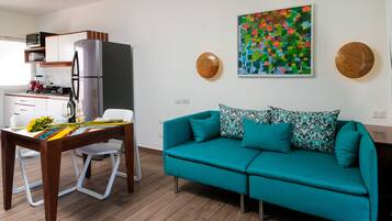 Una cocina moderna con refrigerador, microondas y estufa. Hay un sofá color turquesa y una mesa de comedor con sillas.
