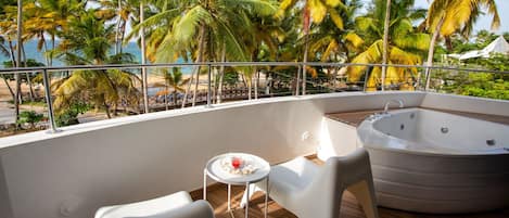 A balcony with a hot tub, white chairs, and a small table with a drink.