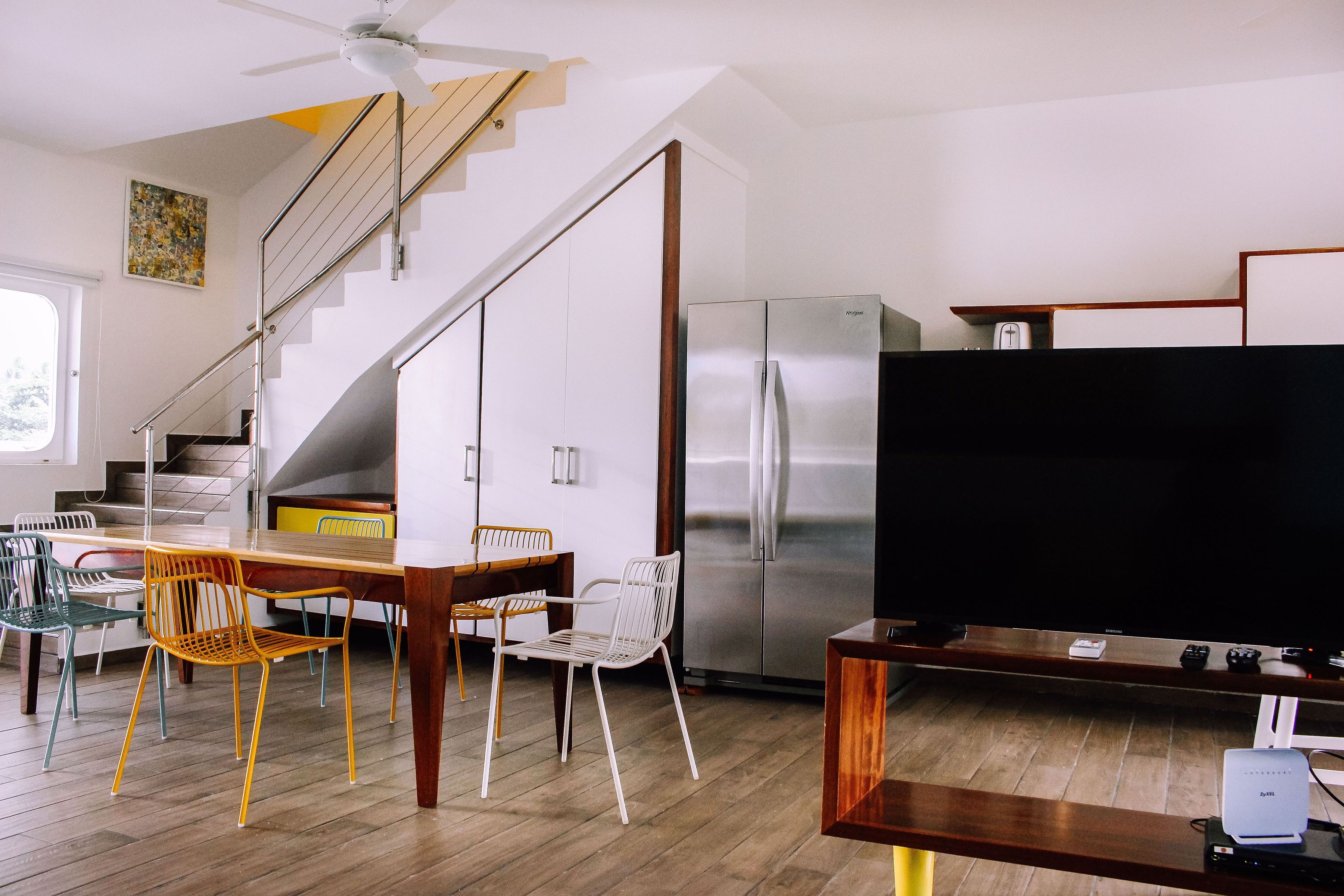 Une cuisine moderne avec un réfrigérateur en acier inoxydable, une table à manger en bois et des chaises.
