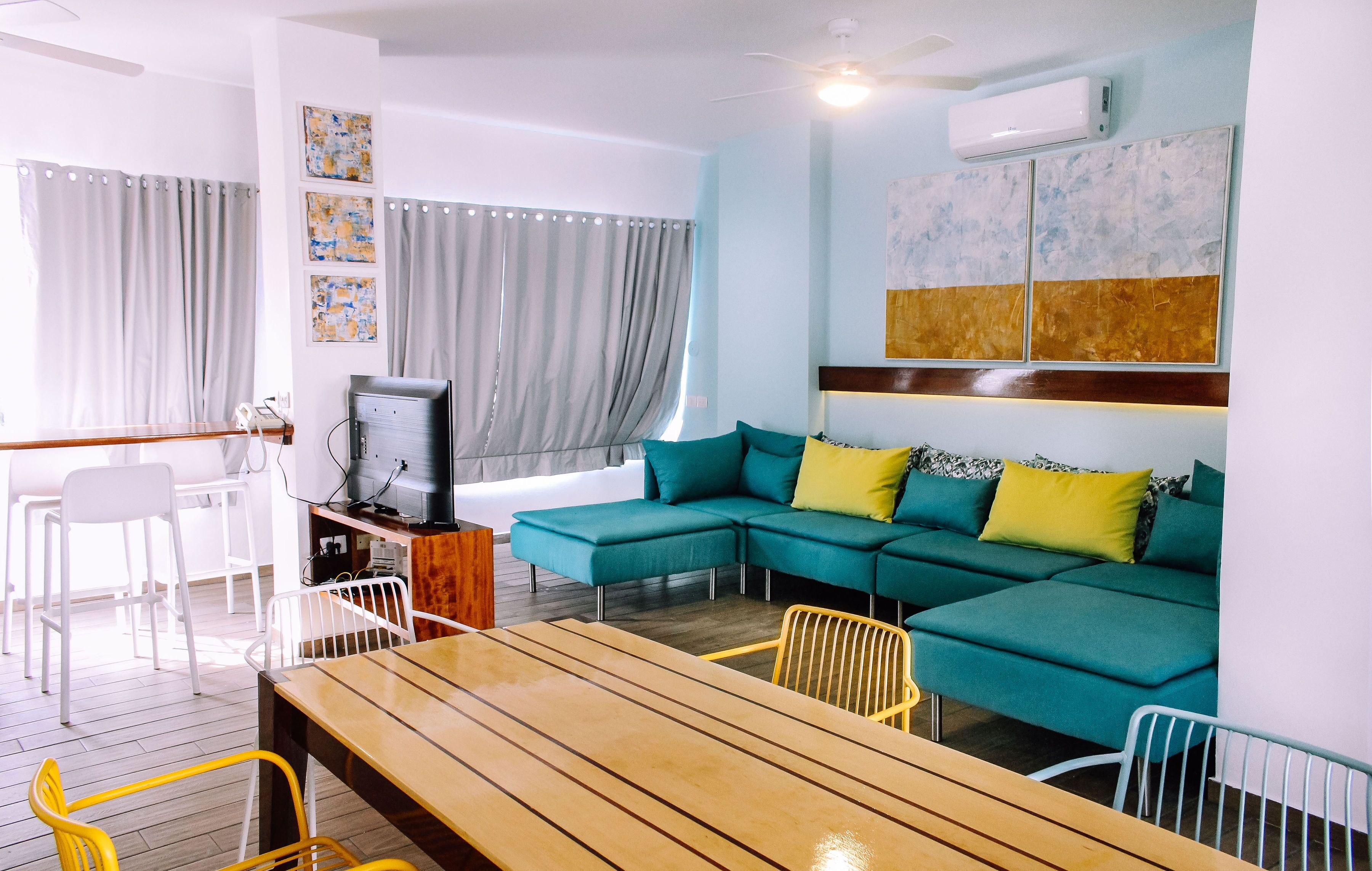 A modern living room with a teal sofa, wooden coffee table, and white chairs.