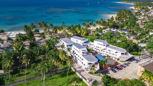 Et resort med flere bygninger, en swimmingpool og udsigt til stranden.