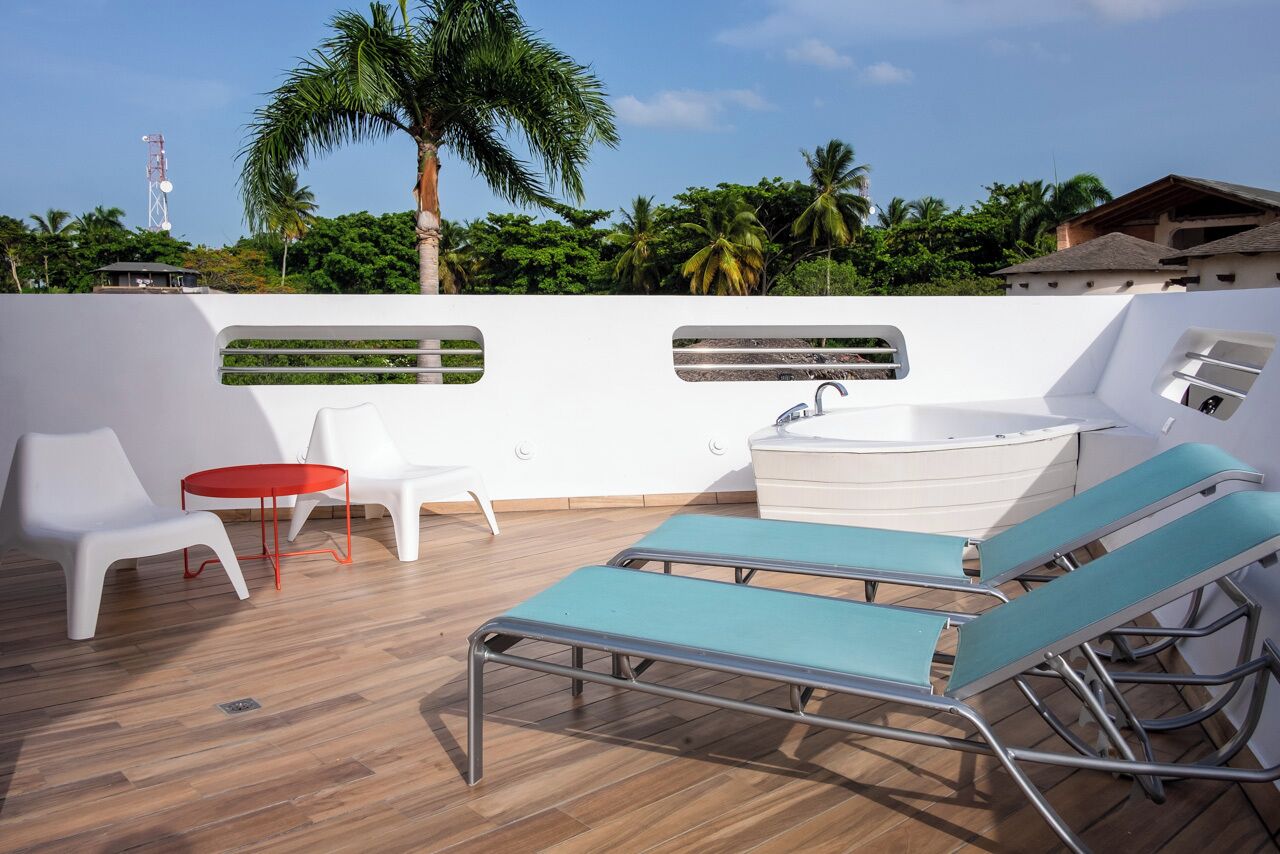 A rooftop terrace with lounge chairs, a small table, and a hot tub.
