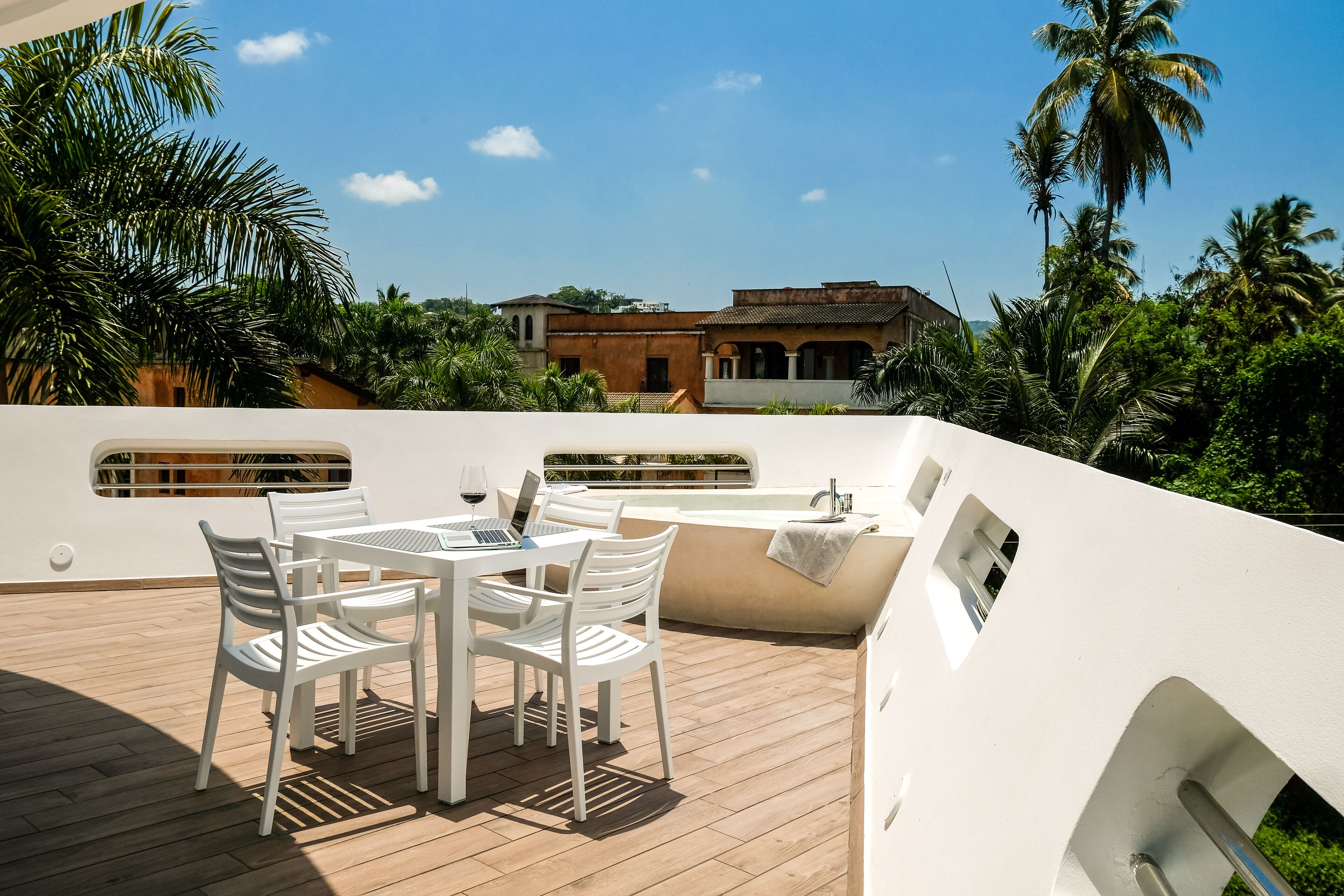 Terraza en la azotea con mesa y sillas, una computadora portátil y una zona de estar con una toalla.