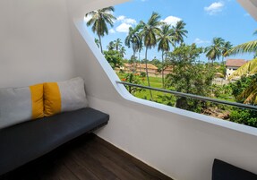 Un balcón con vista a palmeras y casas.