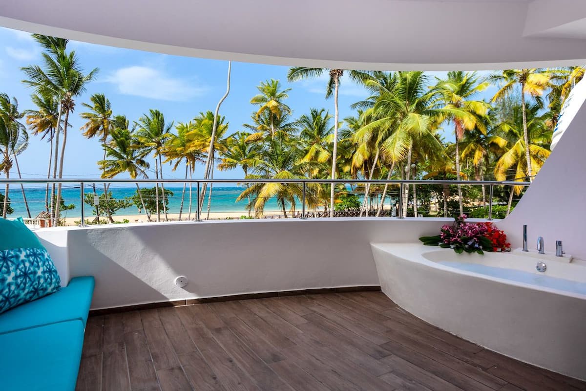 A balcony with a view of a beach and palm trees.