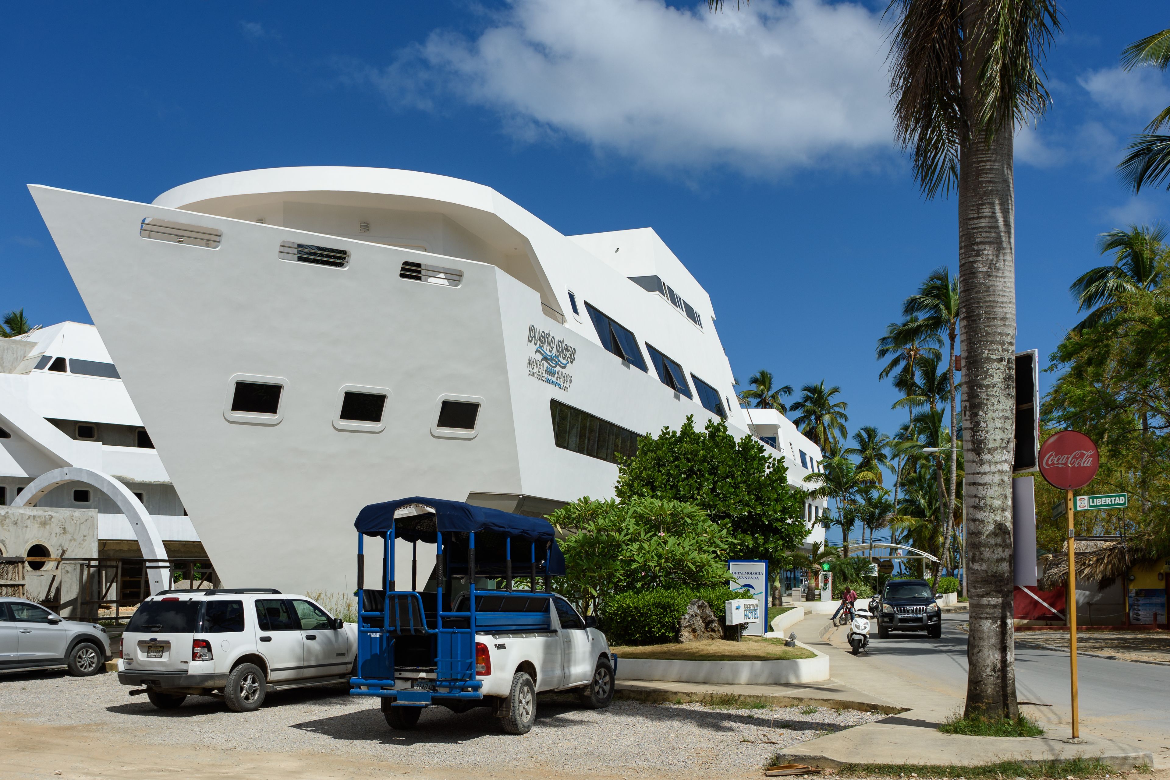 A large white yacht docked near a modern building with a sign reading "Puerto Rico".