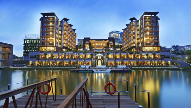 A waterfront hotel with multiple high-rise buildings, a dock, and a calm lake.