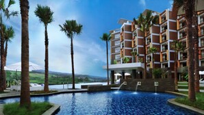 A hotel with a swimming pool, palm trees, and a view of a mountain.