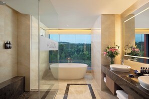 A modern bathroom with a freestanding bathtub, a large mirror, and a view of the outdoors. - Aston Sentul Lake Resort & Conference Center (Sentul City)