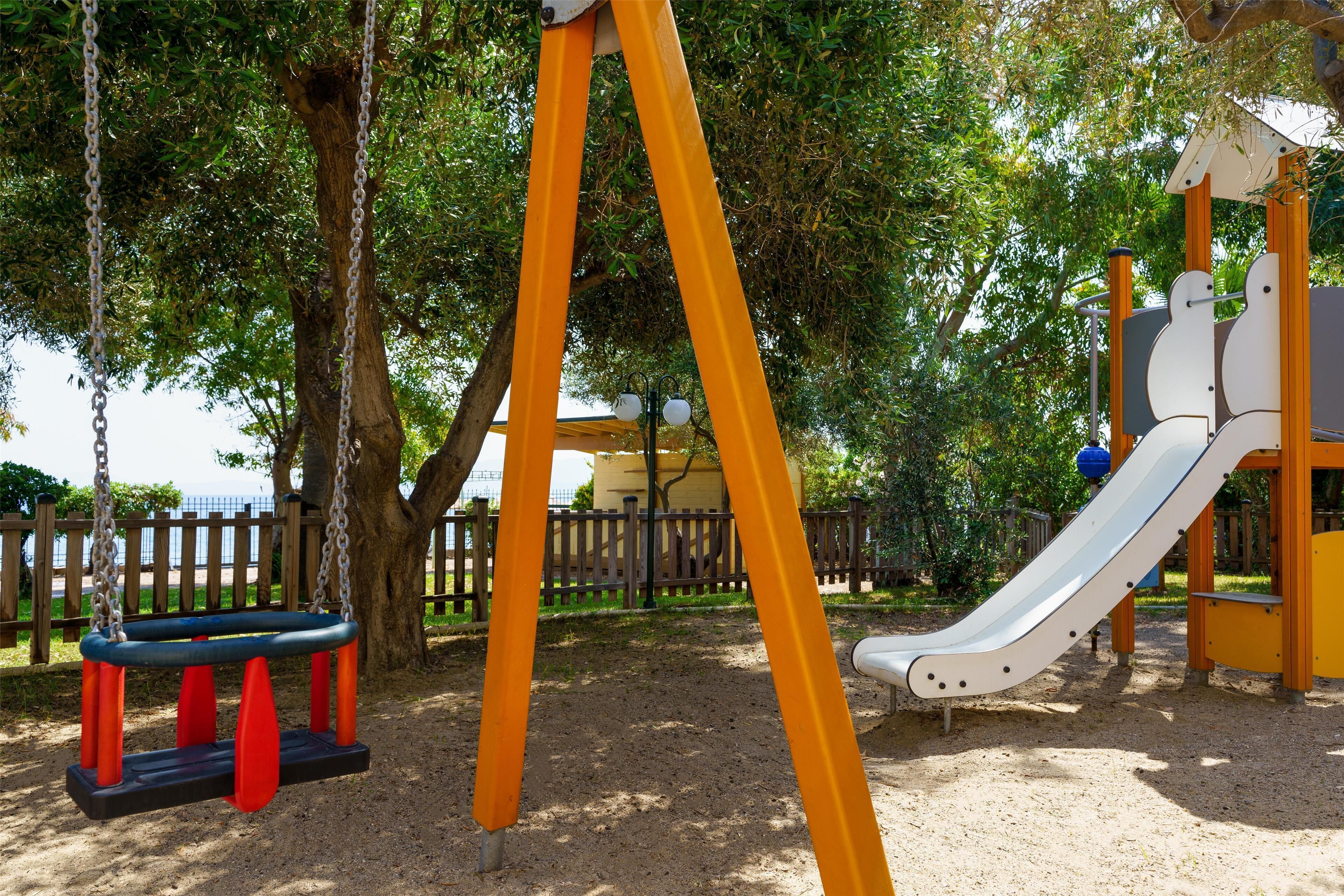 Un parc infantil amb un cadireta i un tobogan.
