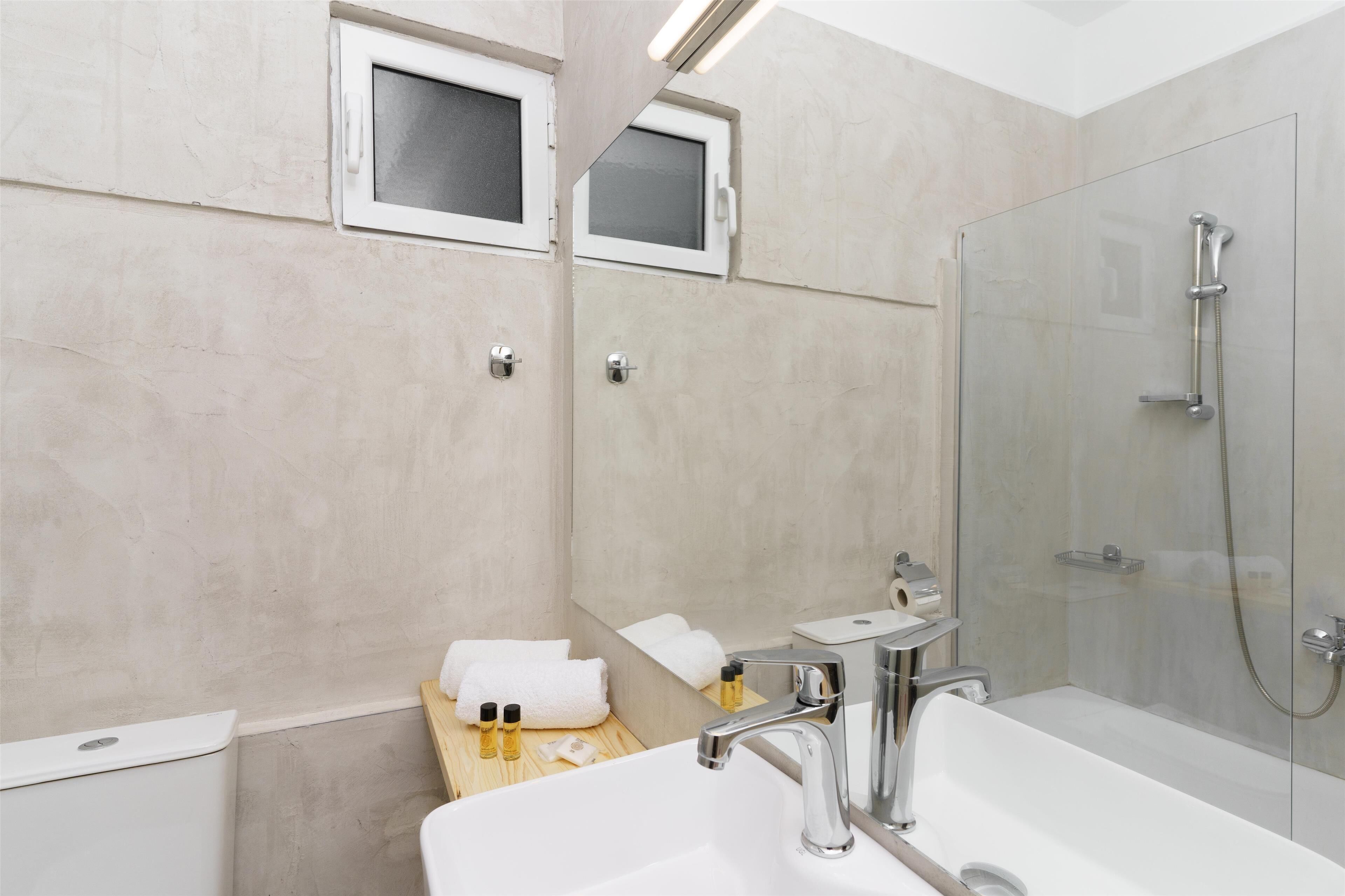 Un baño moderno con cabina de ducha de vidrio, un lavabo blanco y un mueble de tocador de madera.