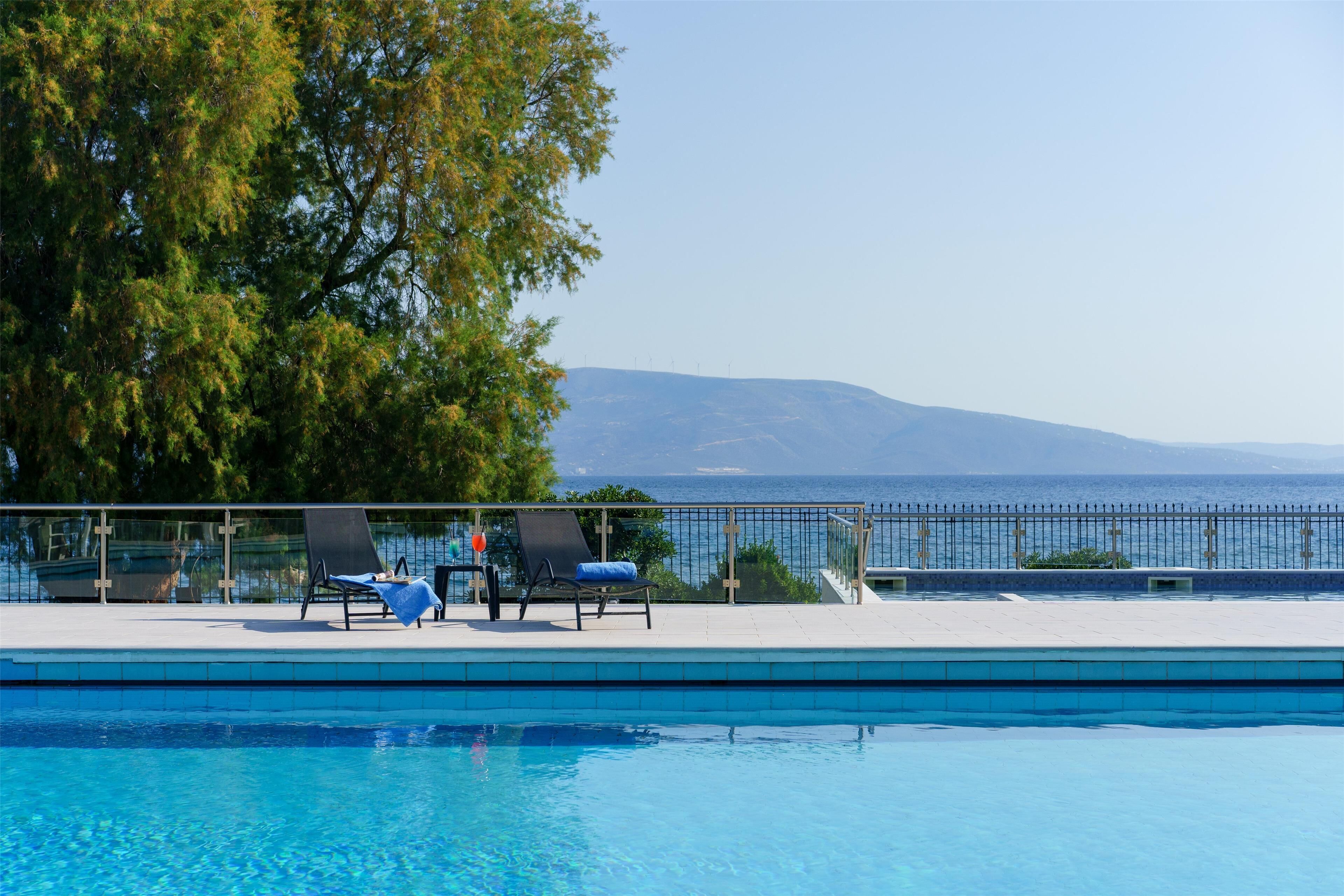 A swimming pool with lounge chairs and a view of the sea.