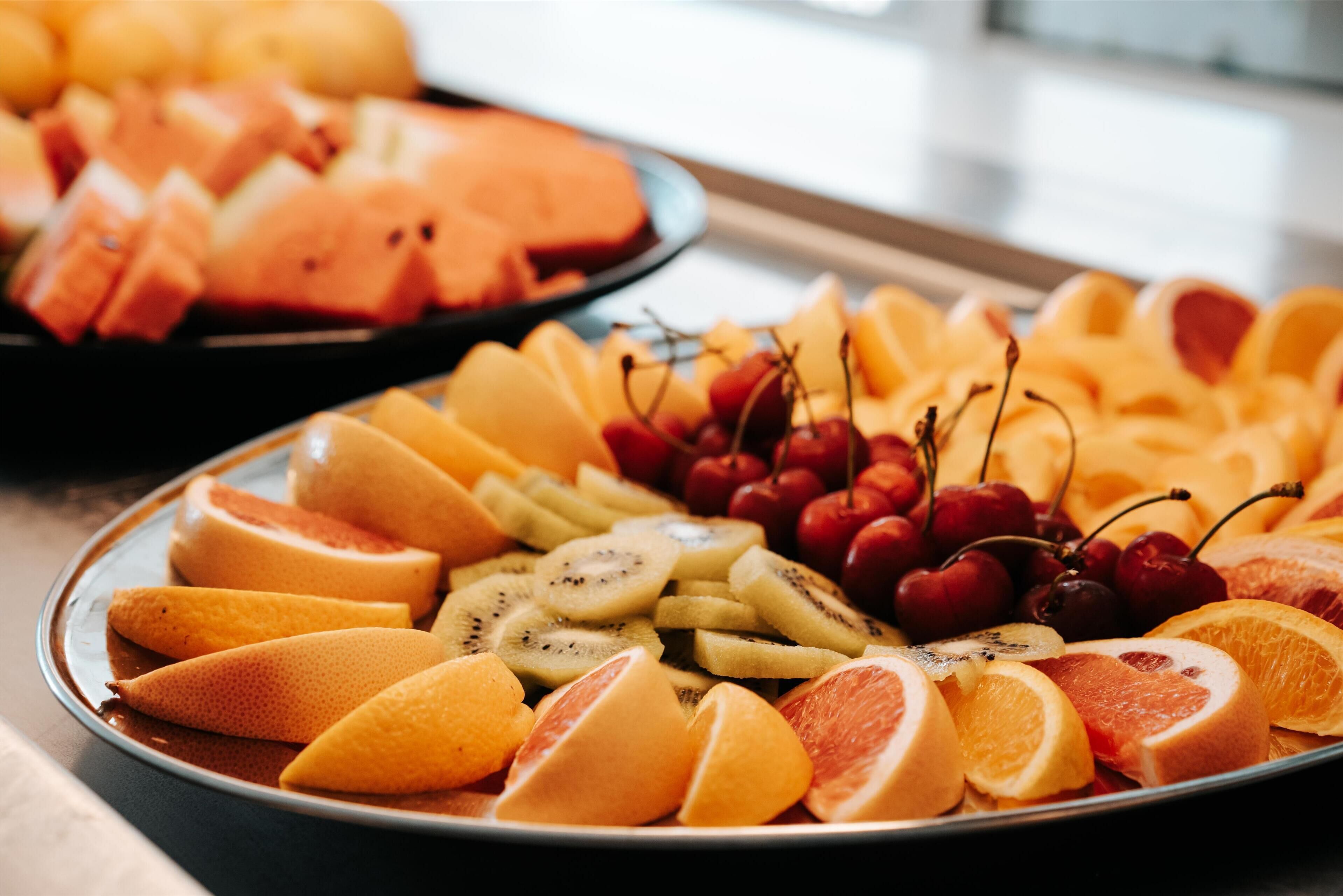 Un assortiment de fruits coupés, comprenant notamment des oranges, des kiwis et des cerises.