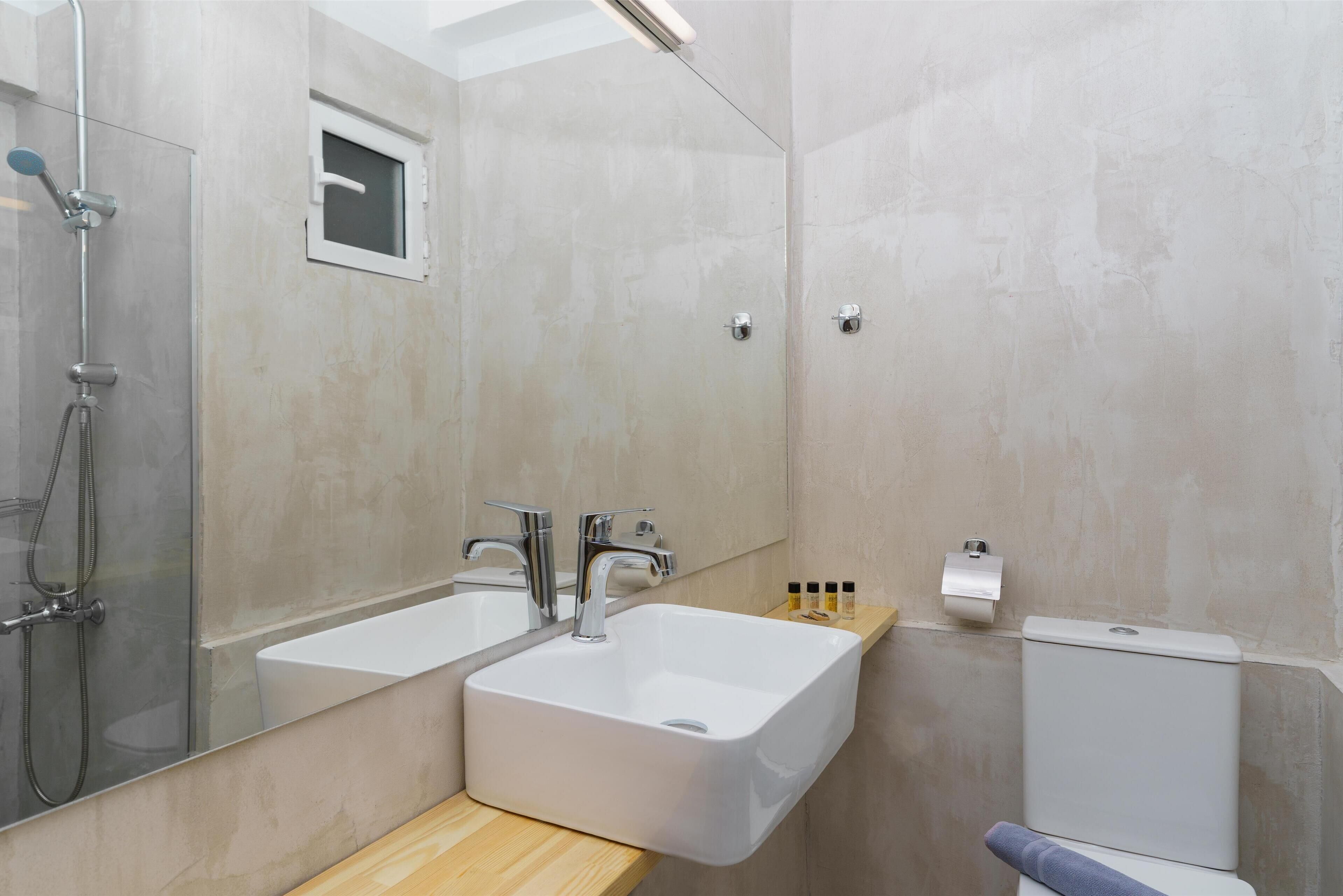 A modern bathroom with a double sink, a shower, and a toilet.