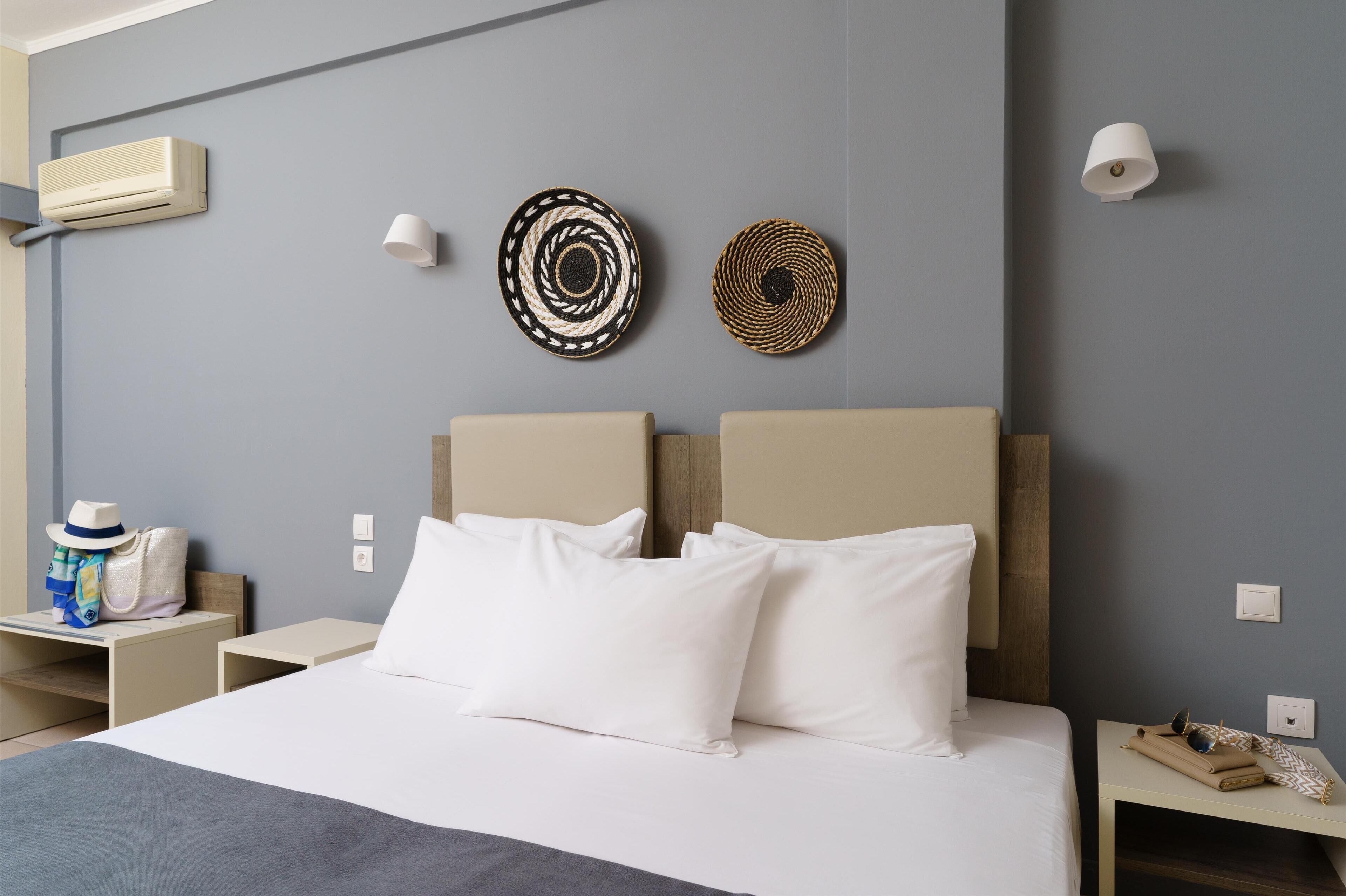 Habitación de hotel con una cama, dos lámparas de pared y un aire acondicionado instalado en la pared.