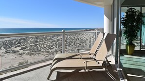 A balcony with two sun loungers overlooking a beach with sparse vegetation and a clear blue sky. - Luna Blanca by Kivoya (Puerto Peñasco)