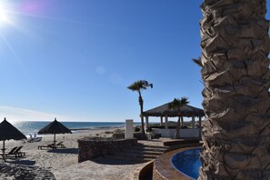 Na praia, areia branca, espreguiçadeiras, guarda-sóis 