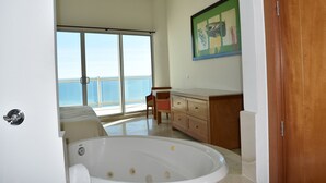 A spacious room with a large bathtub, a wooden vanity, and a sliding glass door leading to a balcony with a view of the ocean. - Luna Blanca by Kivoya (Puerto Peñasco)