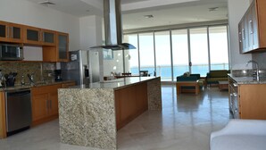 A modern kitchen with granite countertops, stainless steel appliances, wooden cabinets, and a large island. - Luna Blanca by Kivoya (Puerto Peñasco)
