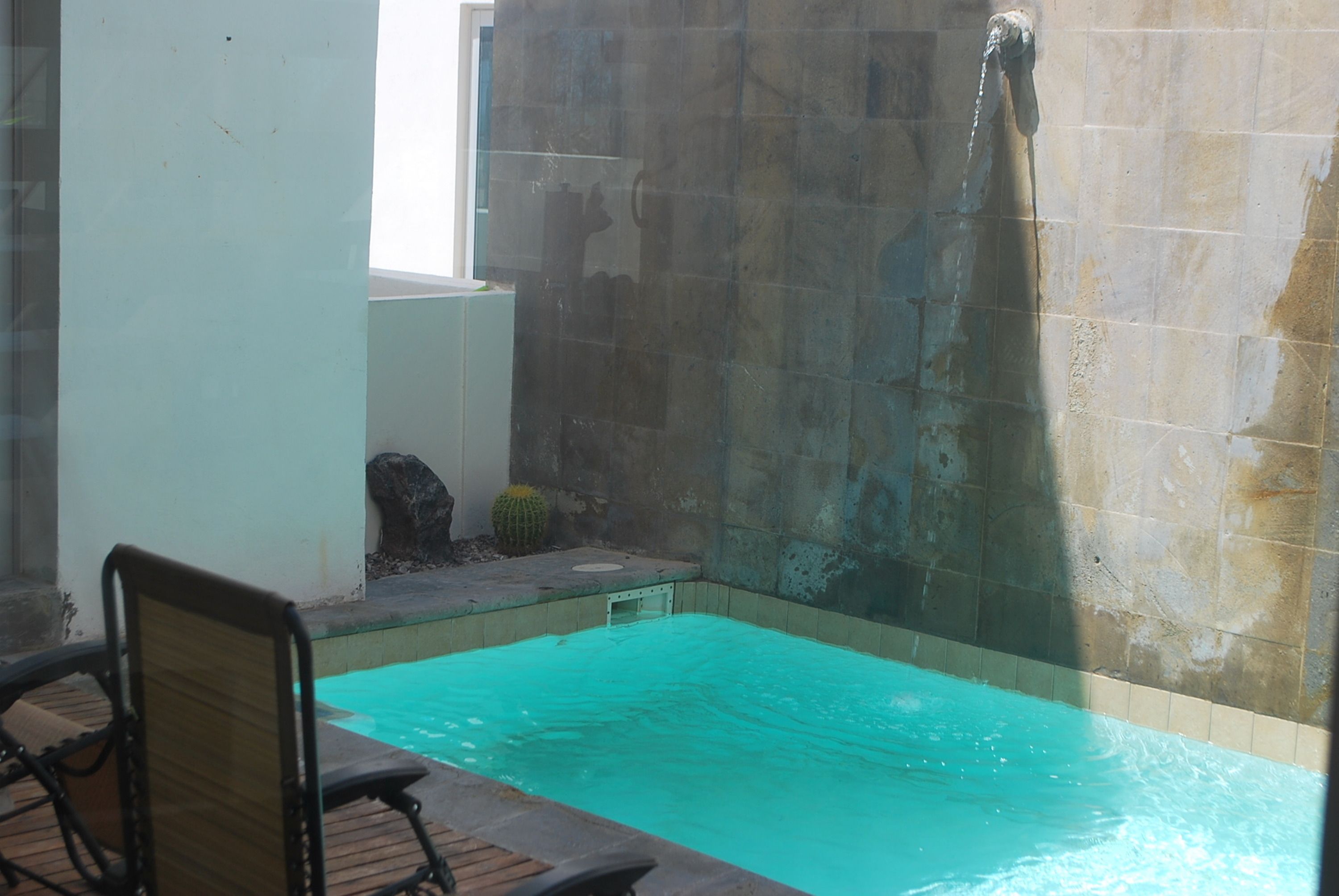 Una piscina pequeña al aire libre con muelle de madera y una silla.