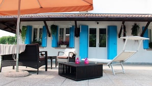 An outdoor seating area with a table, chairs, and a sun lounger.
