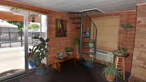 Una habitació amb una banca de fusta, una escala en espiral i plantes en testos.