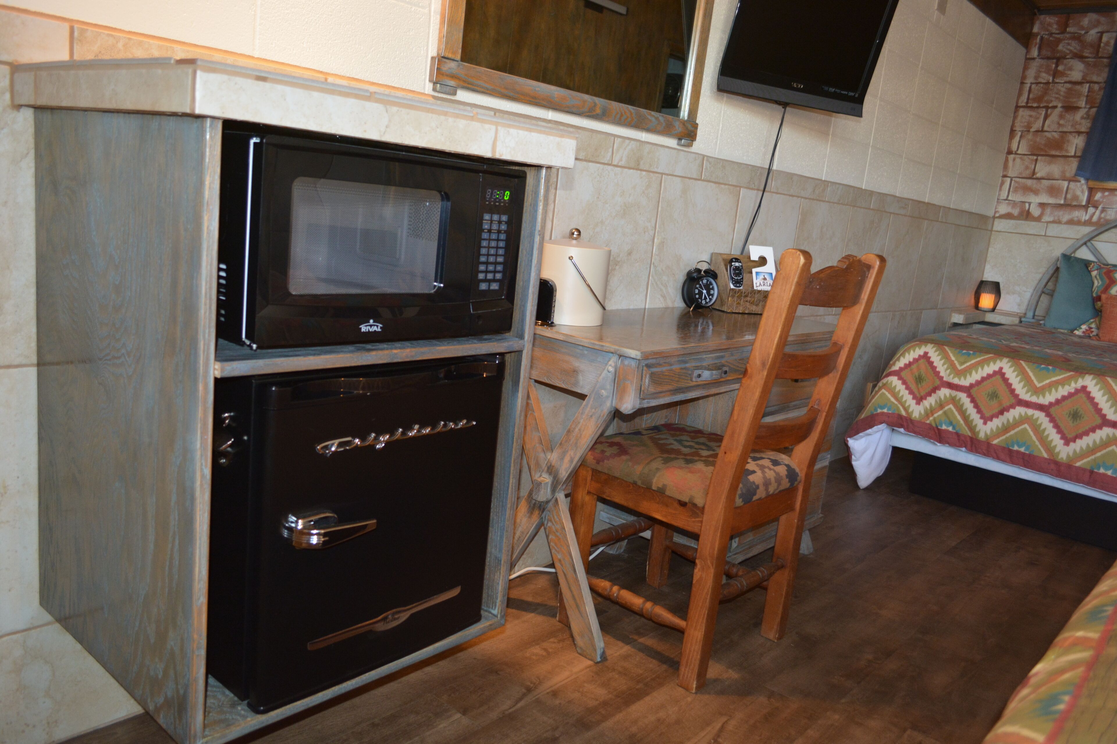 A compact kitchenette with a microwave, oven, and a small table with a chair.