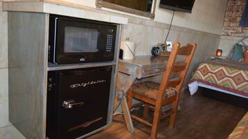 A compact kitchenette with a microwave, oven, and a small table with a chair.