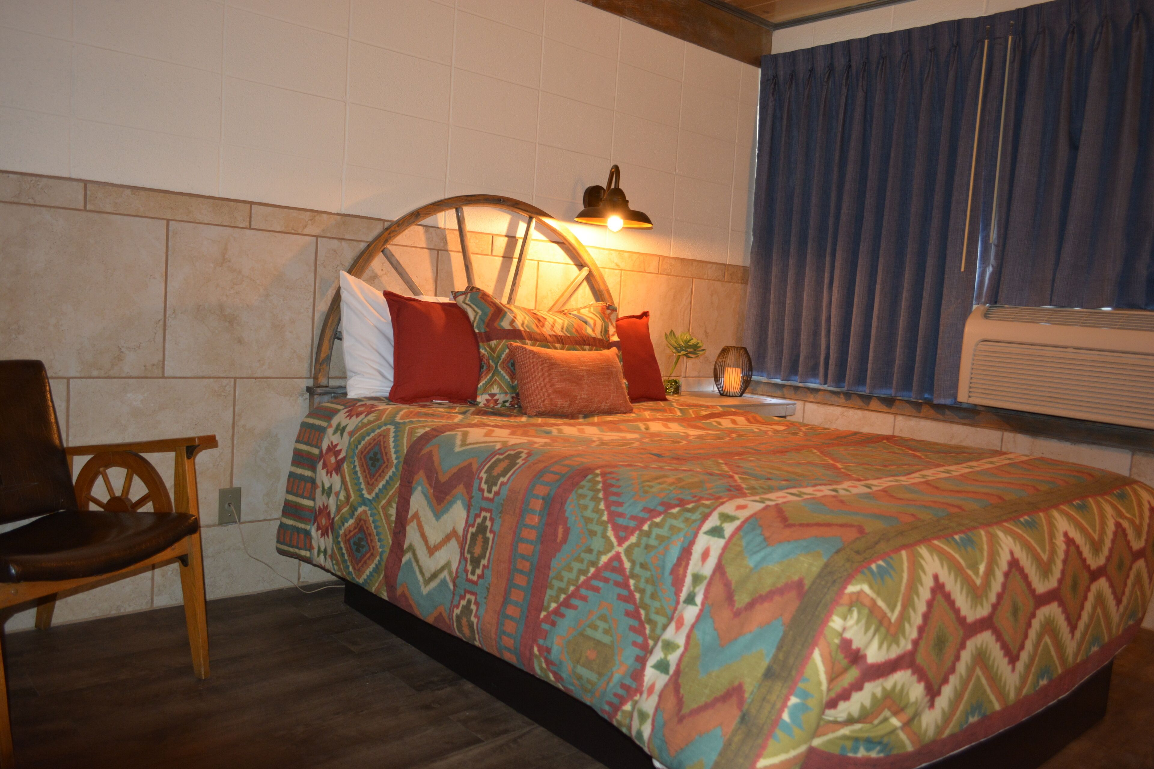 A bedroom with a bed, a chair, a lamp, and a window with curtains.