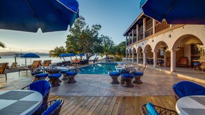 A poolside area with wooden decking, lounge chairs, and umbrellas.