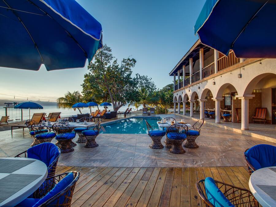 A poolside area with wooden decking, lounge chairs, and umbrellas.
