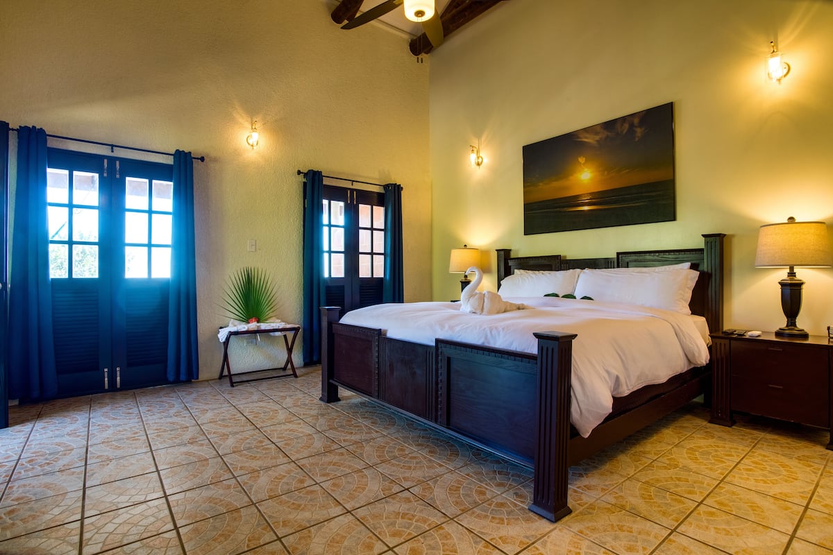 Un dormitorio ordenado con una cama grande, dos mesitas de noche y un cuadro colgado en la pared.