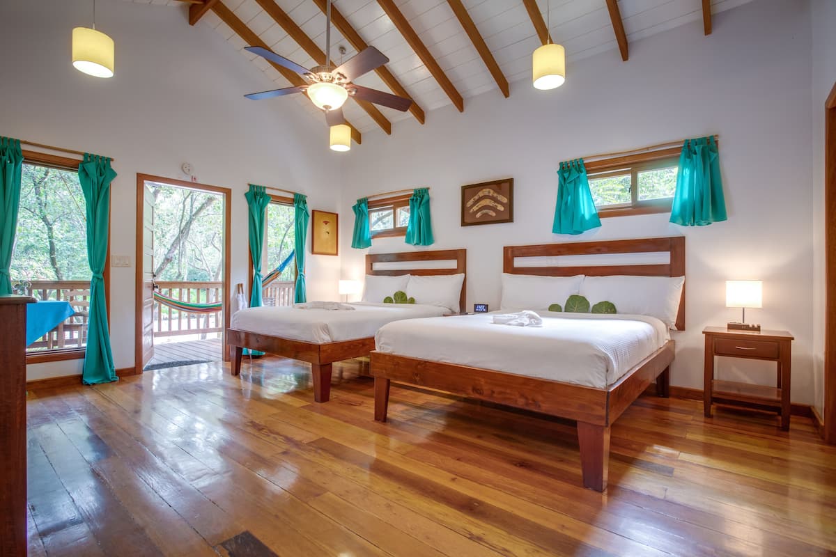 Una habitación con dos camas de madera, un ventilador de techo y suelo de madera.